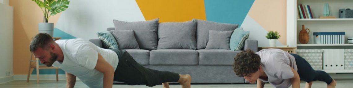 Male and female yoga students are practising downward dog position at home focused on practice on mats, people are moving simultaneously doing asanas.